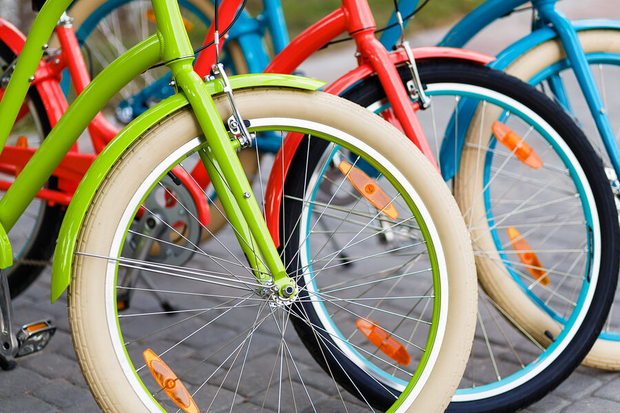 Closeup of three bright colored city urban woman bikes tires row outdoors in the park
